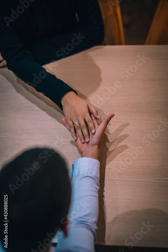 Top view of a happy couple having a romantic date in a restaurant wearing a proposal ring