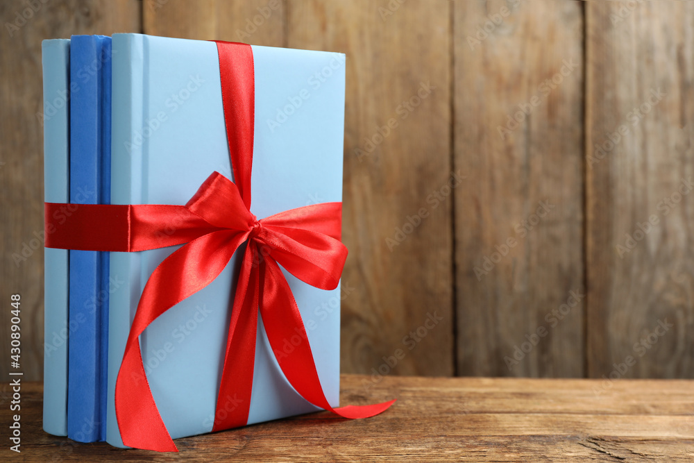 Fototapeta premium Different books tied with red ribbon on wooden table, space for text