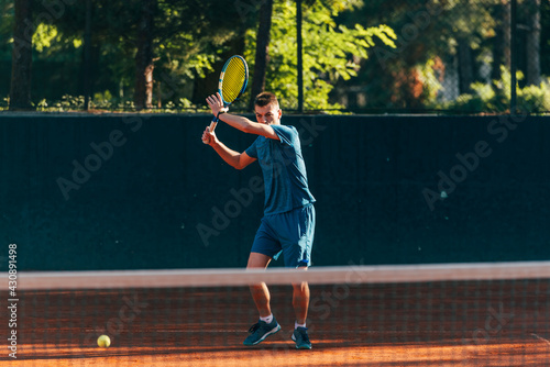 Professional equipped male tennis player beating hard the tennis ball with a forehand