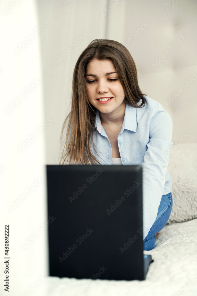 girl at home studying distance learning. a student sits at a laptop in her bed. remote work. online education of a young girl girl at home studying distance learning. a student sits at a laptop in her bed. remote work. online education of a young girl