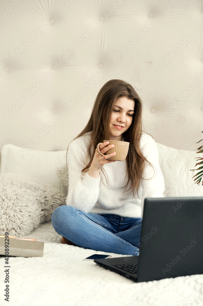 girl at home studying distance learning. a student sits at a laptop in her bed. remote work. online education of a young girl girl at home studying distance learning. a student sits at a laptop in her bed. remote work. online education of a young girl