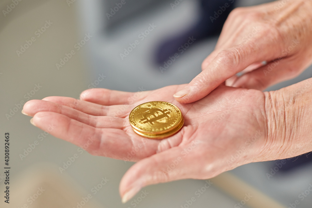 Old woman holds bitcoin coins in her hand. Senior citizen happy life concept Old woman holds bitcoin coins in her hand. Senior citizen happy life concept