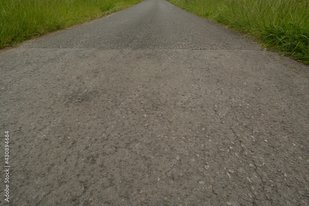Direct asphalt road among grass. Forward direction straight ahead. Rural landscape with covered road. Nobody in landscape scene. Jorney to the future. Way to the freedom. Way covered with asphalt.