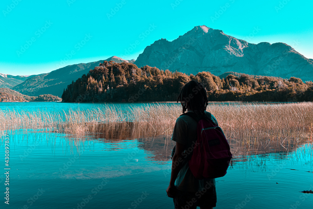 hombre joven con rastas mirando hacia el horizonte en un paisaje de montañas