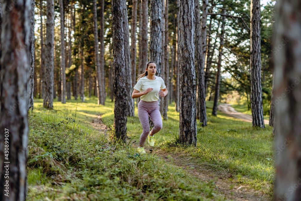 Side view full length of young caucasian woman running trough the woods in nature outdoor jogging in sunny day - sport fitness and recreation concept real people copy space Side view full length of young caucasian woman running trough the woods in nature outdoor jogging in sunny day - sport fitness and recreation concept real people copy space