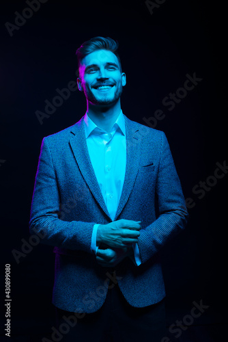 Young handsome model posing in a studio in a trendy neon light. Fashionable man in a stylish suit. Vibrant color. Bright colorful light effects. Disco style. Overlay. Gel filter. Supersaturated