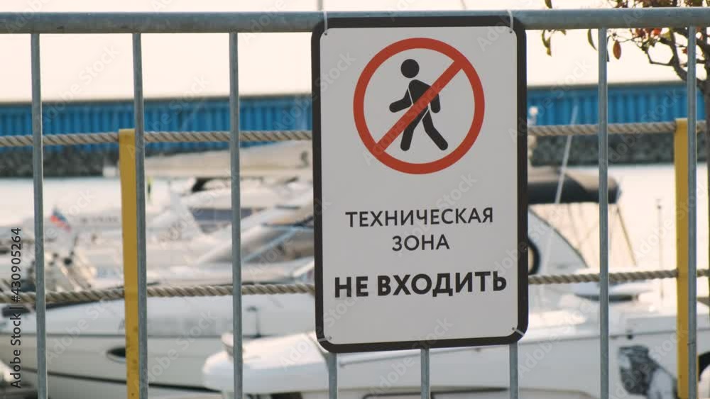 No trespassing sign in marina with boats in background. white prohibition sign with black outline of person in circle crossed out. Inscription in Russian language TECHNICAL ZONE DO NOT ENTER No trespassing sign in marina with boats in background. white prohibition sign with black outline of person in circle crossed out. Inscription in Russian language TECHNICAL ZONE DO NOT ENTER