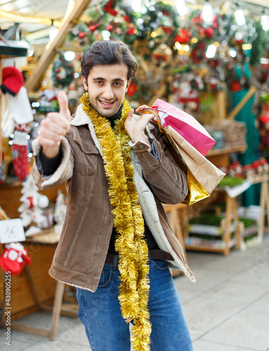 Portrait of young man happy with purchases at Christmas market