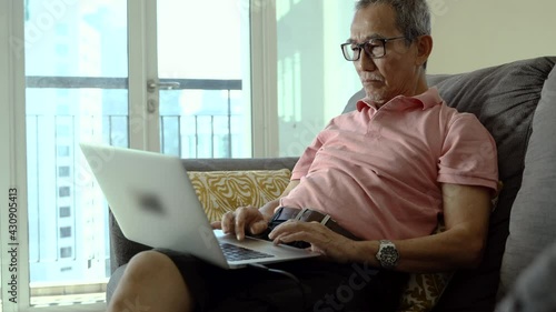 Technology concept, senior citizen using laptop at home.