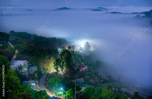The city sunk in the night fog with bright electric lights in the mist creating a fanciful, impressive scene in Da Lat, Vietnam