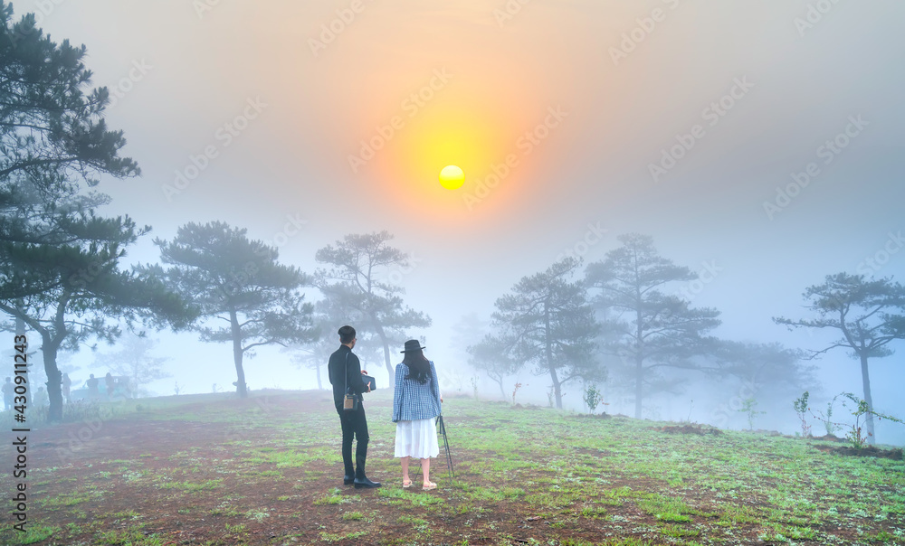 Tourists watching the dawn on a misty morning pine hill on the top of the highlands of Da Lat, Vietnam Tourists watching the dawn on a misty morning pine hill on the top of the highlands of Da Lat, Vietnam