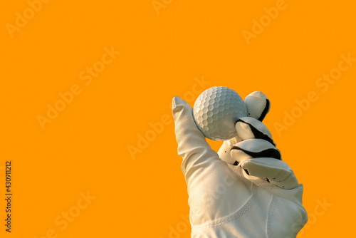 Golfer wearing golf glove showing golf ball on hand holding with orange color background. photo