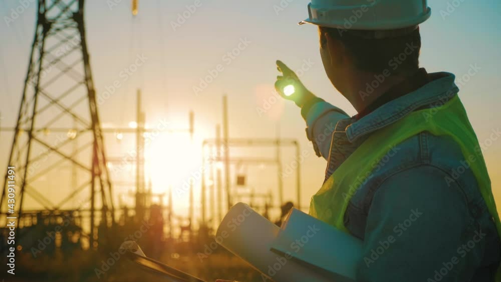 Industry energy business concept. Silhouette electrical engineer a working near tower with electricity at sunset time. Electrical worker inspect voltage electricity pylon. Power generation industry. Industry energy business concept. Silhouette electrical engineer a working near tower with electricity at sunset time. Electrical worker inspect voltage electricity pylon. Power generation industry.