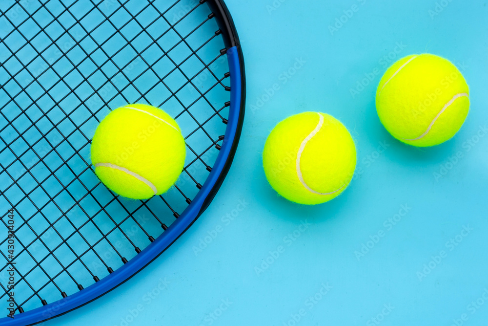 Tennis racket with balls on blue background.