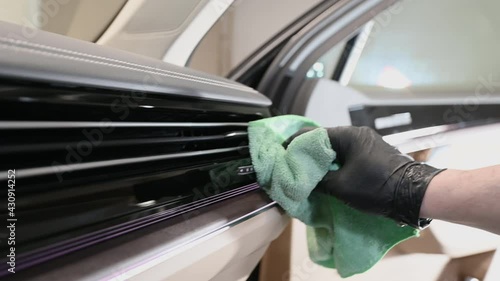 The man cleans the car from the dust using a damp cloth. Car cleaning, close up. A man rubs a dashboard.