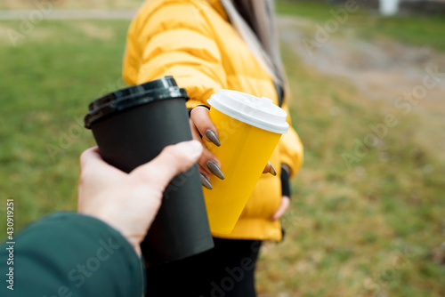 Fotografia Couple of people clink of disposable coffee cups on the street, close-up