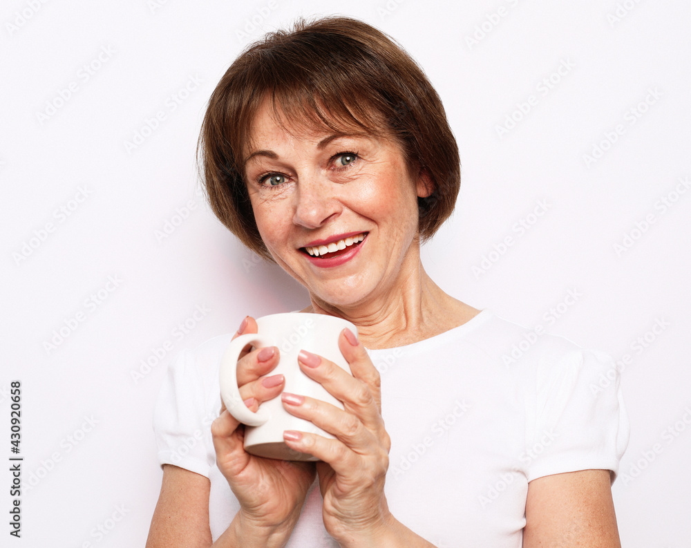 Cheerful elderly woman wear casual with cute smile holding a cup of coffee over white background. Cheerful elderly woman wear casual with cute smile holding a cup of coffee over white background.
