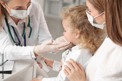 Pediatrician examining little girl in clinic