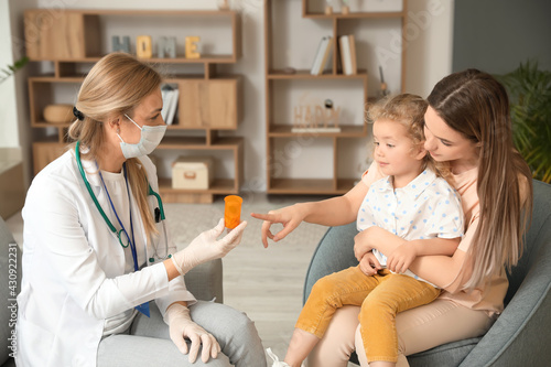 Pediatrician giving medicine to little girl at home