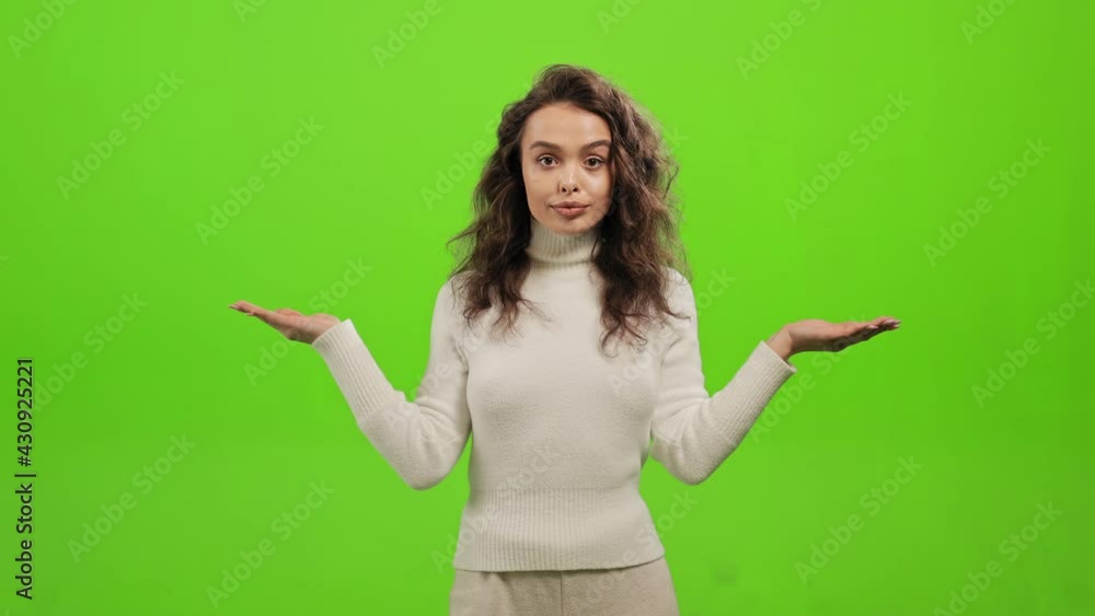 The woman is standing and looking at the camera. She is waving her hands and waving her head that she doesn't know. She is standing on a green background. Green screen. 4K The woman is standing and looking at the camera. She is waving her hands and waving her head that she doesn't know. She is standing on a green background. Green screen. 4K