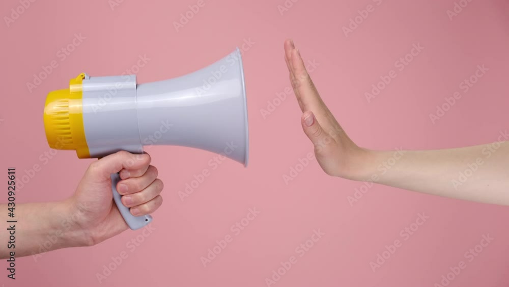 Close up of unrecognizable male holding bullhorn public address megaphone woman show stop palm gesture protest demonstration, isolated over pink studio wall. Hot news, announce communication concept Close up of unrecognizable male holding bullhorn public address megaphone woman show stop palm gesture protest demonstration, isolated over pink studio wall. Hot news, announce communication concept