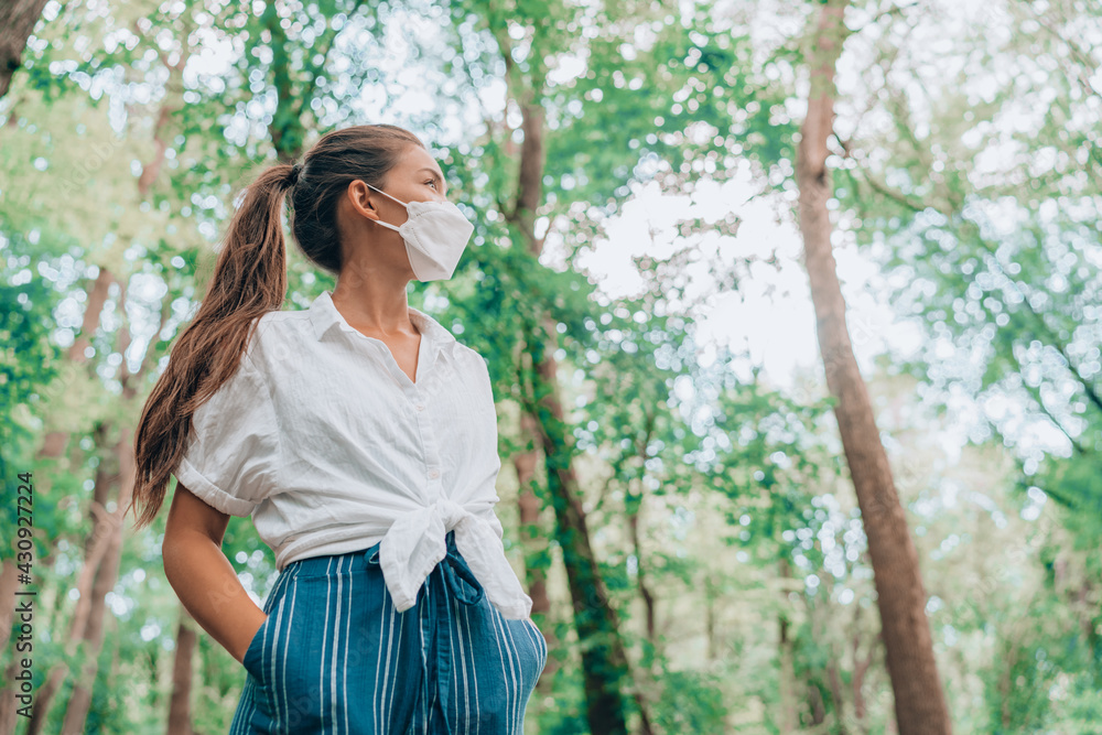 Walking in nature woods wearing face mask during coronavirus pandemic. Asian woman in sustainable eco friendly clothing fashion fabric. People lifestyle sustainability concept. Walking in nature woods wearing face mask during coronavirus pandemic. Asian woman in sustainable eco friendly clothing fashion fabric. People lifestyle sustainability concept.