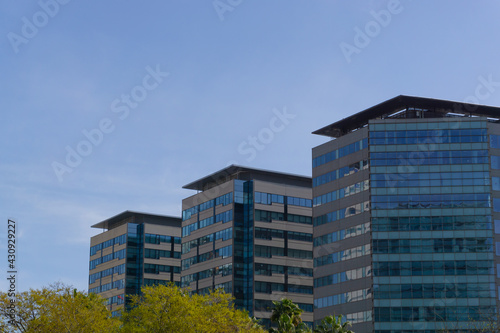 Image of three office buildings with large windows and clear sky