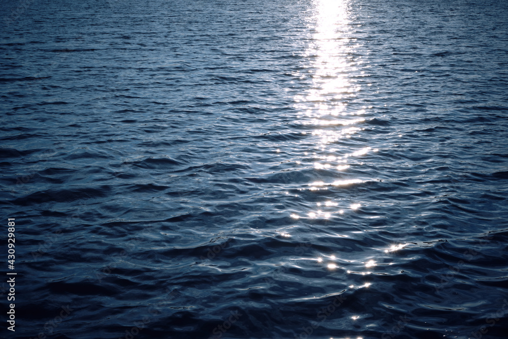 Background, blue expanse of ocean water at evening sunset with reflected rays of sun on waves. Background, blue expanse of ocean water at evening sunset with reflected rays of sun on waves.