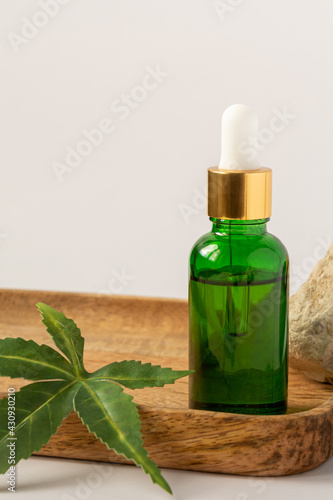 green glass bottle with CBD oil, THC tincture and hemp leaves on a white background. minimalism style. Organic cosmetics Cosmetics with CBD oil
