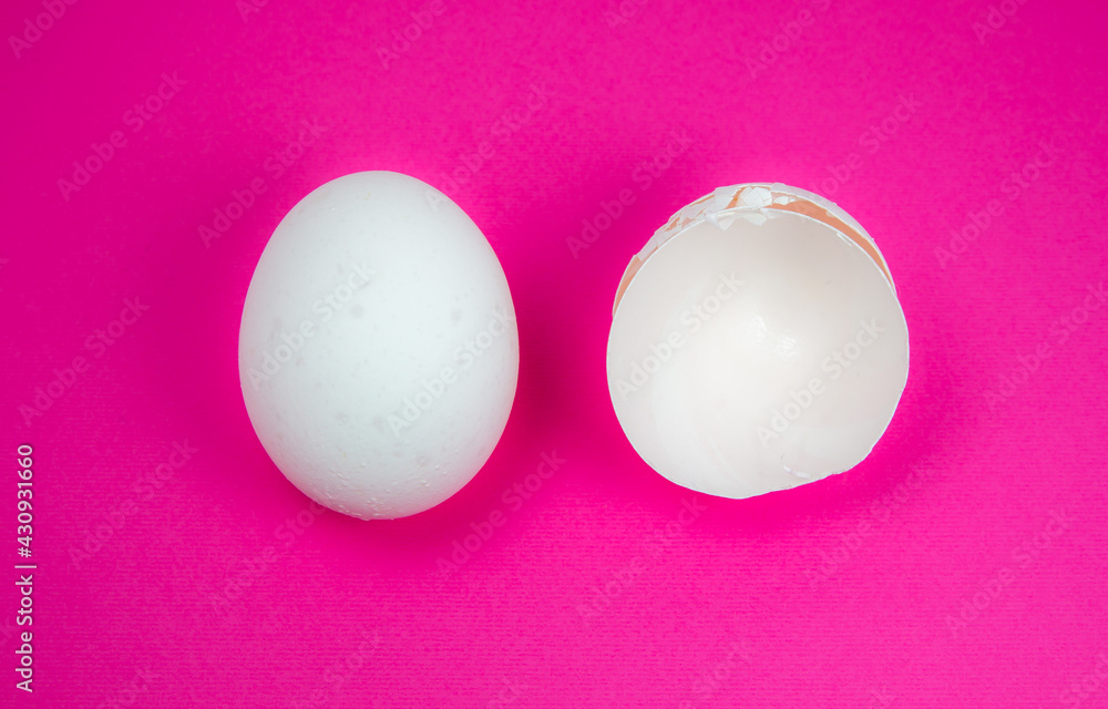 White egg and  eggshell on the pink background. Copy space. Minimalism, original and creative photo. Beautiful wallpaper. Easter holidays.