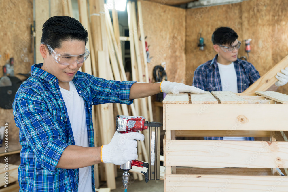 Carpenter hammering nails into wood with a automatic nailer. Carpenter worker with machine at wood workshop. Carpenter hammering nails into wood with a automatic nailer. Carpenter worker with machine at wood workshop.