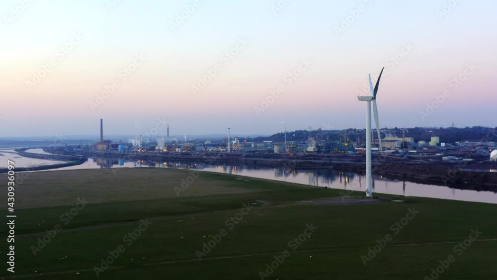 Large chemical plant drone establishing shot. drone jib up slow shot passing wind turbines after sunset in the UK. Large chemical plant drone establishing shot. drone jib up slow shot passing wind turbines after sunset in the UK.