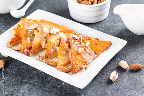 Shahi tukra/tukda or Double ka meetha is a bread pudding Indian sweet of fried bread slices soaked in rabid or sweet saffron milk garnished with dry fruits, selective focus photo