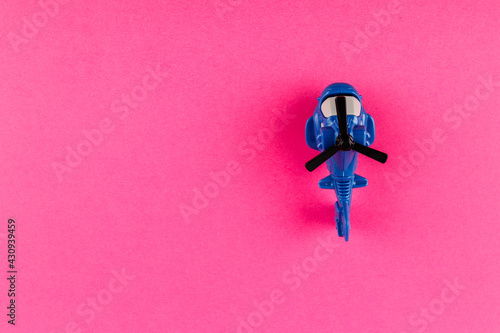 Small plastic helicopter with copy space on pink background.