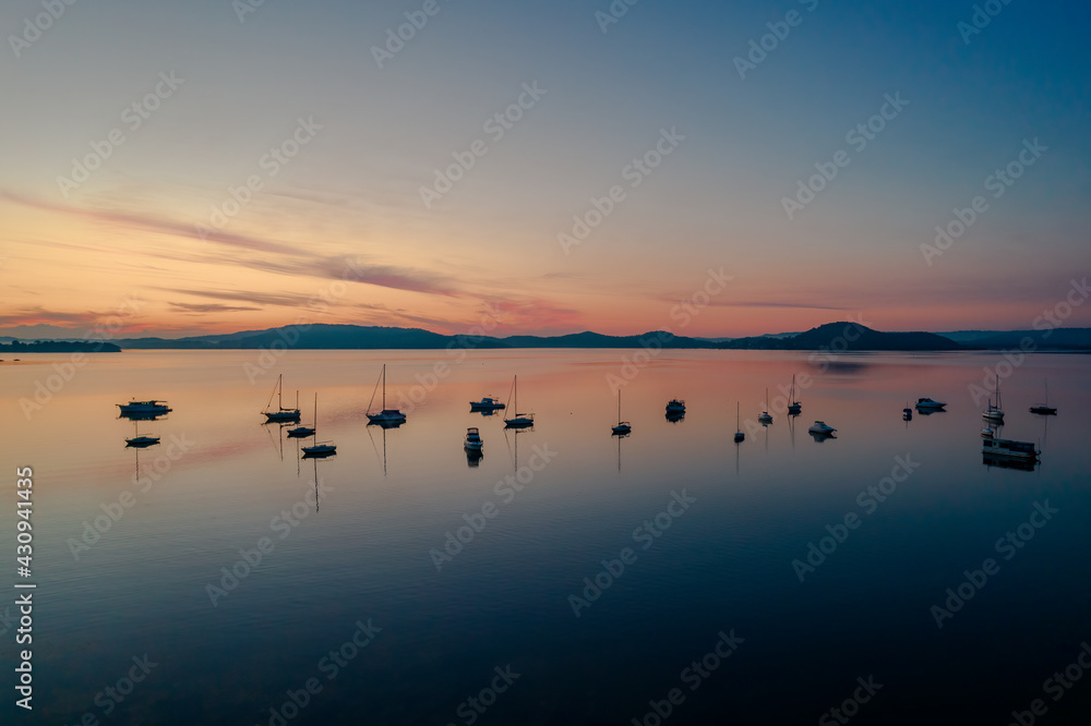 Fototapeta premium Sunrise waterscape with boats, light cloud and reflections