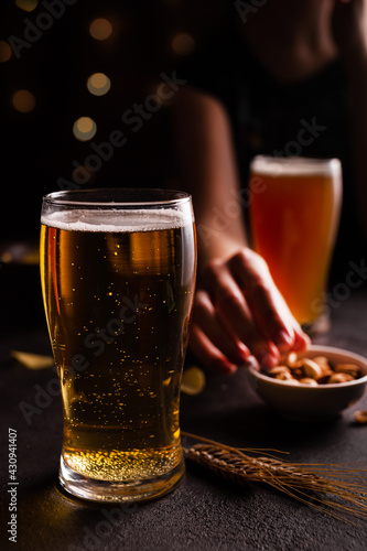 A glass of beer on the table. Woman eating snacks