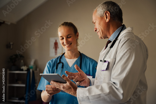 Male and female doctors smiling looking at positive results on digital tablet.