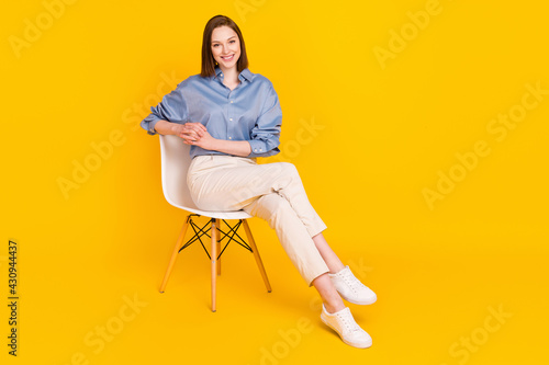 Photo of sweet adorable young lady dressed blue outfit sitting chair smiling isolated yellow color background