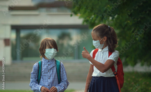 Children go back to school. Cute pupils with backpacks. Boy and girl in safety masks