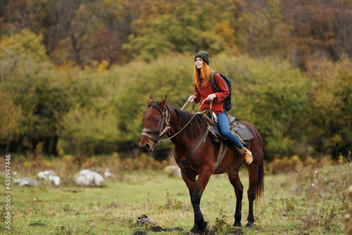 woman hiker with a backpack rides a horse in the mountains nature friendship