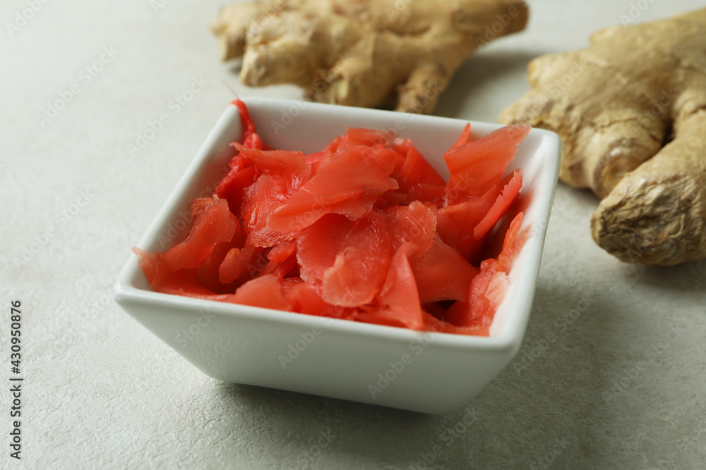 Bowl with red pickled ginger and ginger on white textured background Bowl with red pickled ginger and ginger on white textured background