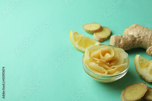 Bowl with pickled ginger, lemon and ginger on mint background