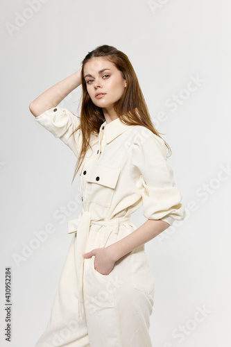 stylish woman model in a white suit on a light background holds her hand behind her head