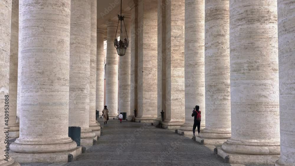 Colonnade of St. Peter's Square with tourists strolling and taking pictures. Vatican City, Europe Colonnade of St. Peter's Square with tourists strolling and taking pictures. Vatican City, Europe
