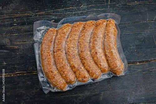 Vacuum-packed meat sausages on a wooden background.