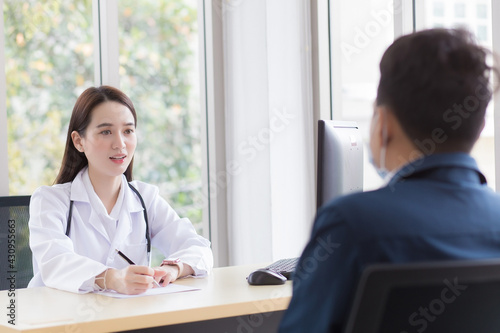 Wallpaper Mural Asian professional  woman doctor who wears medical coat talks with a man patient to consult and suggest healthcare information to him. Torontodigital.ca