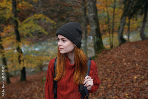 woman hiker walks in the forest in autumn in nature near the river and leaves landscape