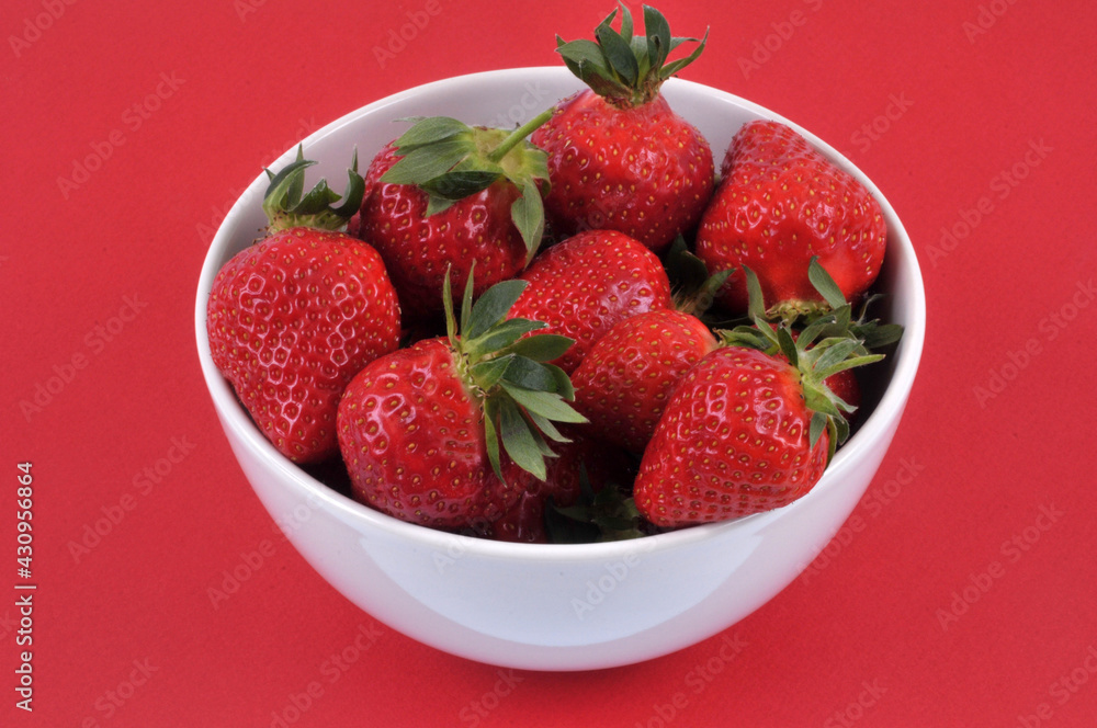 Bol de fraises gariguettes en gros plan sur fond rouge Bol de fraises gariguettes en gros plan sur fond rouge