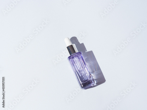 Hyaluronic acid serum peptide purple glass bottle on gray background