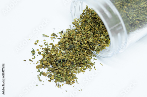 Ground buds of medical marijuana stored in plastic jar. Closeup on medical hemp blend isolated on white background. CBD, medical hemp in container.